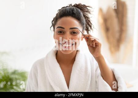 Donna afroamericana styling sopracciglia con pinzette in bagno Foto Stock