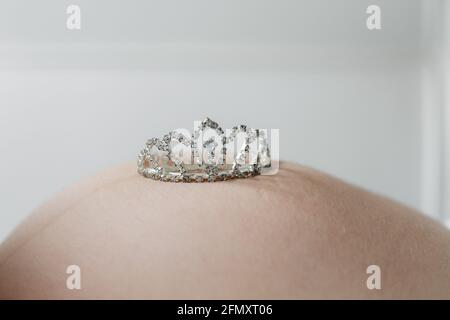 Gravidanza baby ventre attesa neonato. Corona giocattolo sulla pancia Foto Stock