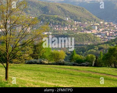 Una valle con una città in un paesaggio montano - Vista incorniciata da albero Foto Stock