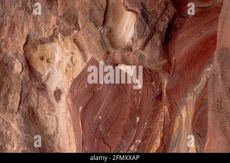 Arenaria rosa rossa multicolore con segni di agenti atmosferici ed erosione, motivi e strutture di formazione rocciosa creati da ossidi di ferro e manganese Foto Stock