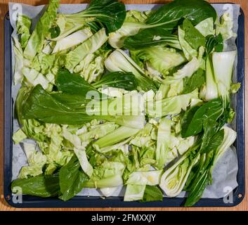 Bok Choy e cavolo con olio e aglio su teglia pronta per essere tostata in forno. Vista dall'alto. Foto Stock