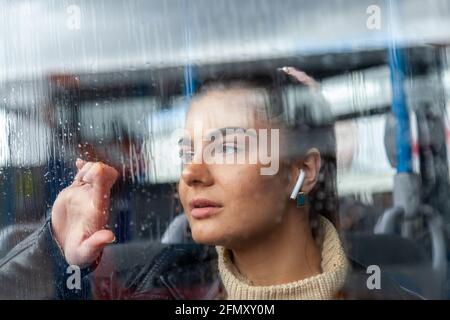 Ragazza che si stende dalla finestra piovosa su un autobus Foto Stock