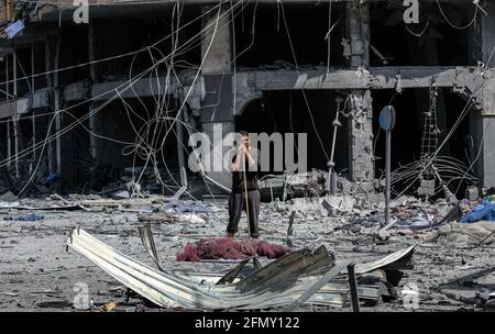 Gaza, Palestina. 12 maggio 2021. Un uomo palestinese si trova tra le macerie della Torre di al-Jawhara, gravemente danneggiata, nella città di Gaza, dopo essere stata colpita dagli attacchi aerei israeliani in mezzo all'escalation della violenza israelo-palestinese. Il Ministero della Sanità della striscia di Gaza, gestita da Hamas, ha affermato che il numero di palestinesi uccisi è salito a 35, di cui 12 bambini, mentre 233 persone sono state ferite. Credit: SOPA Images Limited/Alamy Live News Foto Stock