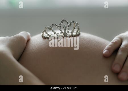 Gravidanza baby ventre attesa neonato. Corona giocattolo sulla pancia Foto Stock