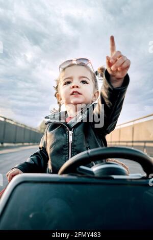 Una ragazza che cavalca un'auto giocattolo Foto Stock