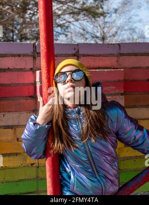 La ragazza adolescente si trova vicino a una parete arcobaleno-colorata all'esterno. Concetto di auto-amore. Stile di vita del bambino. Foto Stock