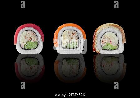 Tre panini di sushi con salmone, tonno e anguilla su sfondo nero Foto Stock