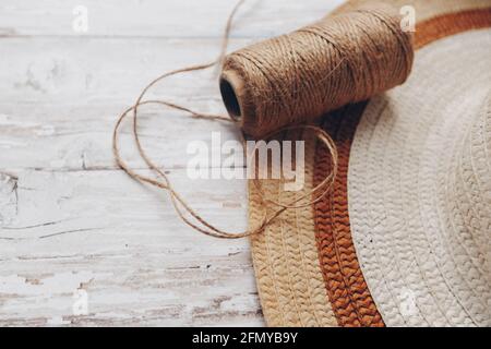 una matassa di spago beige e un cappello di paglia su uno sfondo di legno. spago per l'ago Foto Stock