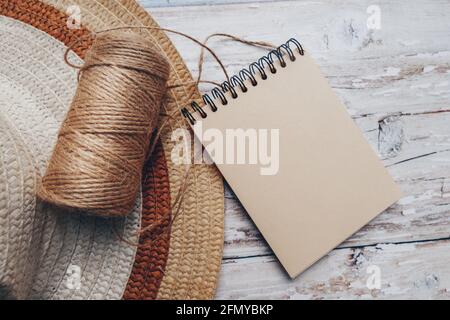 una matassa di spago con un blocco note per il testo e un cappello su sfondo di legno. concetto di taglio e cucitura. Foto Stock