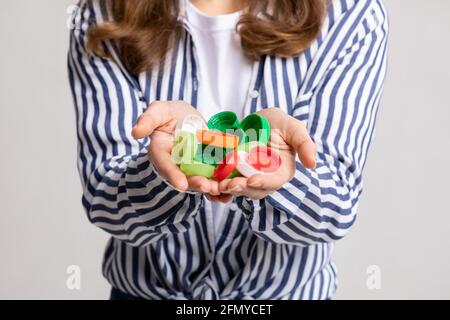 Unriconoscable Female Holding mazzo di coperchi colorati da bottiglie in plastica Nelle mani Foto Stock