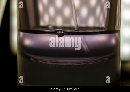 Estremo primo piano macro shot di una bolla formata all'interno di una bottiglia di profumo tutto in uno spruzzo d'acqua su uno sfondo scuro. Foto Stock
