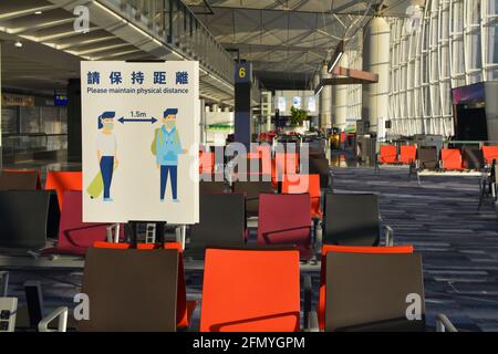 Segno di distanza fisica Covid in un vuoto Chek Lap kok, aeroporto internazionale di Hong Kong. Non molti passeggeri che viaggiano con le attuali restrizioni. Foto Stock