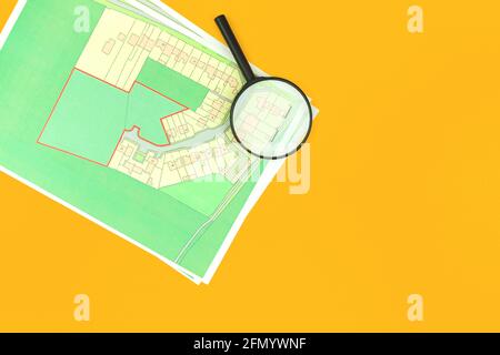 Scegli un terreno di costruzione per la costruzione di case, ufficio immobiliare scrivania con mappa e lente d'ingrandimento sfondo, vista dall'alto foto Foto Stock