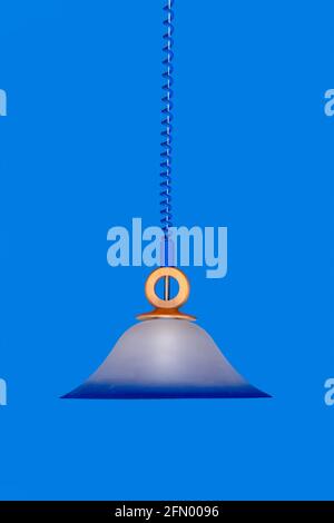 Un lampadario appeso su una corda su uno sfondo di una parete blu Foto Stock