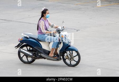 SAMUT PRAKAN, THAILANDIA, 25 2020 LUGLIO, UNA donna con maschera facciale corre una moto Foto Stock