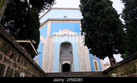 Tomba verde (Yesil Turbe) con ceramica iznik (cini) o piastrelle coperto tomba muro. Porta della tomba dietro gli alberi e le scale stabilite dalla fase iniziale Foto Stock