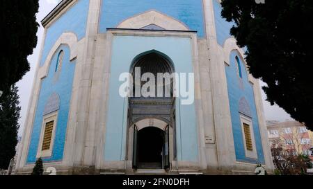 Tomba verde (Yesil Turbe) con ceramica iznik (cini) o piastrelle coperto tomba muro. Porta della tomba dietro gli alberi e le scale stabilite dalla fase iniziale Foto Stock