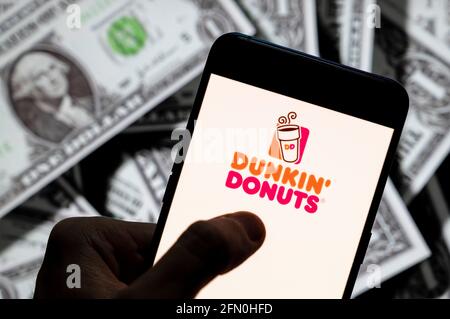 Cina. 21 Apr 2021. In questa illustrazione della foto il logo della multinazionale americana Dunkin' Donuts della catena di caffè e snack, visualizzato su uno smartphone con la valuta USD (dollaro USA) sullo sfondo. Credit: Budrul Chukrut/SOPA Images/ZUMA Wire/Alamy Live News Foto Stock