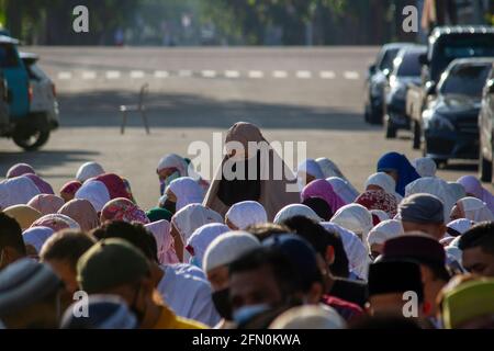 PADANG, INDONESIA, 13 maggio 2021. Milioni di musulmani in Indonesia, nella città di Padang, nella provincia di Sumatra occidentale continuano a fare preghiere per l'Eid sul campo e ad attuare protocolli sanitari mantenendo la loro distanza, anche se il governo ha proibito alle persone di tenere preghiere per l'Eid in congregazione nelle moschee o sul campo. Kariadil Harefa/Alamy Live News - Foto Stock