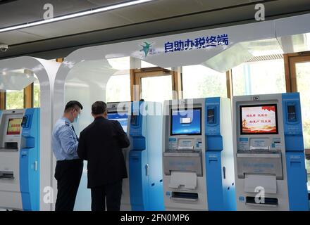 (210513) -- XIONGAN, 13 maggio 2021 (Xinhua) -- UN membro del personale aiuta un cittadino ad utilizzare una macchina self-service per servizi fiscali nell'area self-service del Centro servizi amministrativi New Area di Xiongan, nella Nuova Area di Xiongan, nella Provincia di Hebei, nella Cina settentrionale, 12 maggio 2021. Fondato il 30 maggio del 2018 e composto da diverse aree funzionali, il Centro servizi amministrativi di Xiongan New Area funge da centro di servizi "one-stop" per fornire revisione amministrativa e approvazione e trattare con l'azienda per comodità di imprese e privati. Come uno dei metodi per contribuire a proporre la creazione di un Foto Stock