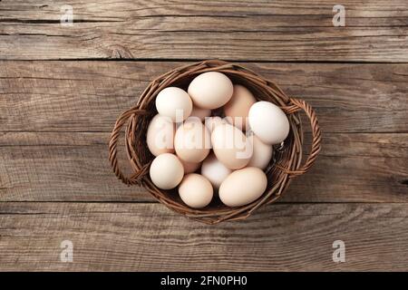 Uova di pollo biologiche in cestino su sfondo di legno. Concetto domestico biologico con uova da galline allevate di free-range e pascolo Foto Stock