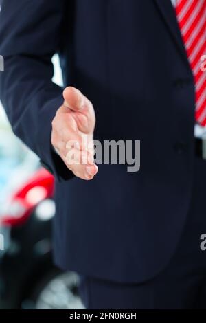 Venditore o venditore auto in concessionaria auto presentando la sua auto nuove e usate nella showroom Foto Stock