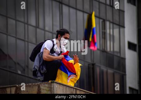 Passo, Colombia. 12 maggio 2021. Demostrator siede con la bandiera della Colombia nel luogo dove si trovava la statua di Antonio Narino, che fu rimossa la notte prima a Pato, Narino il 12 maggio 2021 Credit: Long Visual Press/Alamy Live News Foto Stock