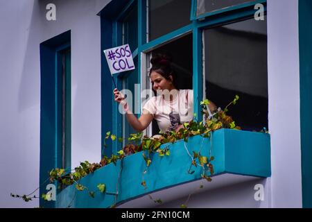 Passo, Colombia. 12 maggio 2021. Donna sbirciata fuori dalla sua finestra con un segno che dice: 'S.O.S. COLl' riferendo la situazione critica del paese a Pato; Narino, Colombia il 12 maggio 2021 Credit: Long Visual Press/Alamy Live News Foto Stock