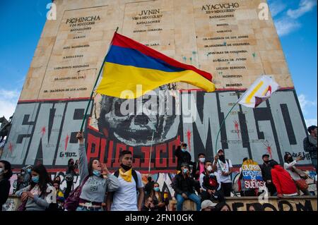 Bogota, Cundinamarca, Colombia. 12 maggio 2021. I manifestanti fanno sventolare bandiere davanti a un murale con il volto dell'ex presidente Alvaro Uribe che recita ''Public Enemy'' come Bogotà, La Colombia entra nella sua terza settimana di proteste anti-governative contro il presidente Ivan Duque Marquez e le morti che si sommano fino a 40 in casi di brutalità di polizia durante lo Sciopero Nazionale, il 12 maggio 2021. Credit: Chepa Beltran/LongVisual/ZUMA Wire/Alamy Live News Foto Stock