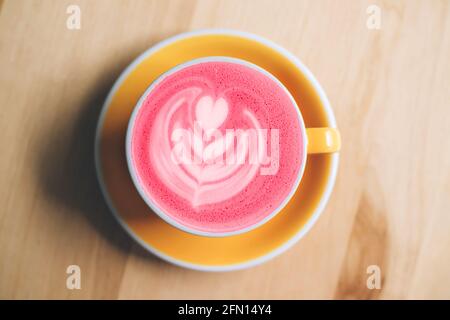 Tazza di latte di barbabietola fresco sano e alla moda con latte art su tavolo di legno. Stile di posa piatto. Foto Stock