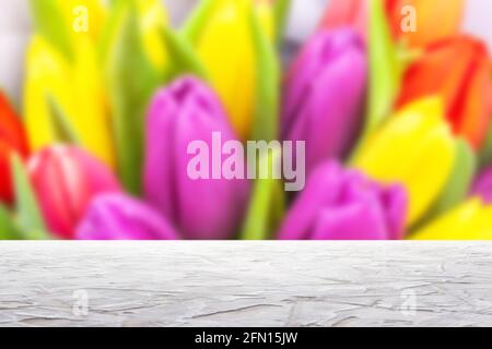 superficie bianca testurizzata su bouquet sfocato di colorati tulipani sfondo Foto Stock