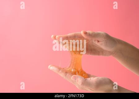 Mani con un pezzo di cera di zucchero appiccicoso su rosa Foto Stock