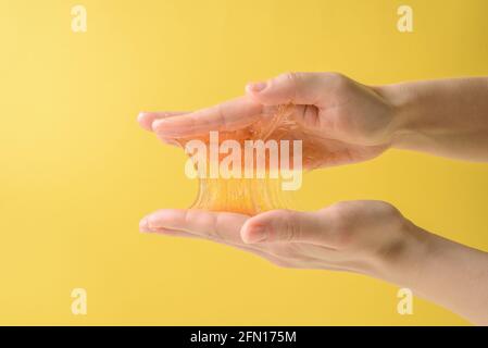 Mani con un pezzo di cera di zucchero appiccicoso sul giallo Foto Stock