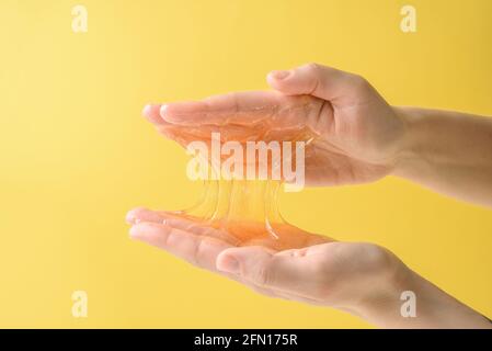 Mani con un pezzo di cera di zucchero appiccicoso sul giallo Foto Stock