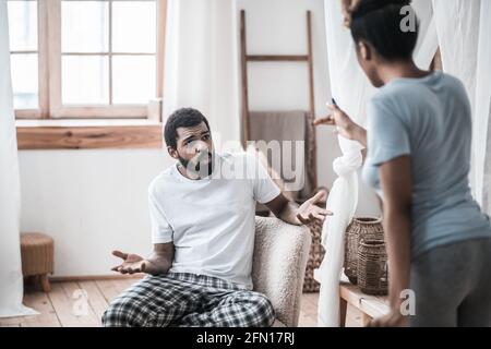 Uomo indignato seduto e moglie in piedi con la schiena Foto Stock