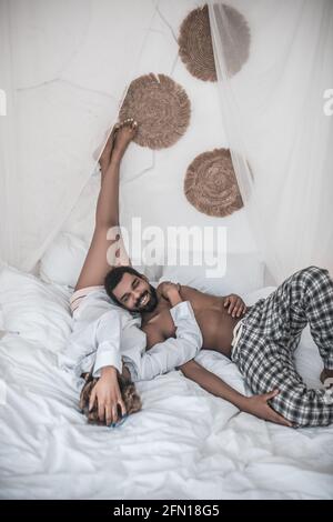 Marito e moglie dalla pelle scura si rilassano sul letto Foto Stock