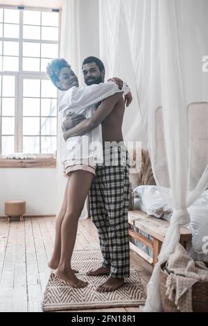 Uomo allegro e donna che abbracciano a casa Foto Stock