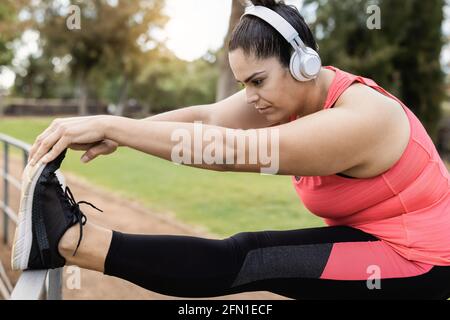 Più donna di taglia che fa la routine di giorno di stretching all'aperto in città park - Focus sul viso Foto Stock