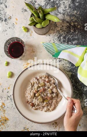 Fagioli e risotto di pancetta italiana. Fagioli sulla parte superiore, bicchiere di vino rosso e asciugamano verde Foto Stock