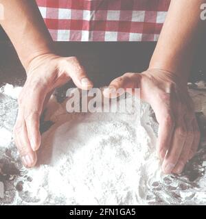 Le mani dello chef preparano l'impasto per la pizza. Cibo sano e naturale fresco Foto Stock