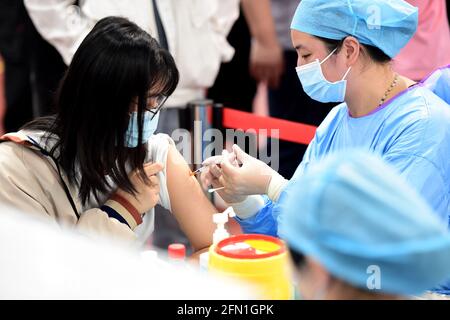 Hefei, provincia cinese di Anhui. 13 maggio 2021. Una donna riceve una dose di vaccino COVID-19 in un sito di vaccinazione presso l'Università agricola di Anhui a Hefei, provincia di Anhui, nella Cina orientale, il 13 maggio 2021. Credit: Huang Bohan/Xinhua/Alamy Live News Foto Stock