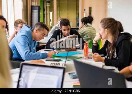 Multiculturale sesta forma studenti, giovani in istruzione, adolescenti che guardano il portatile in sesta forma, studenti che lavorano al portatile Foto Stock