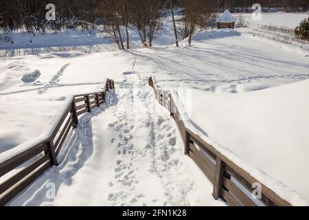 Scale coperte di neve dalla collina alla riva del fiume Foto Stock