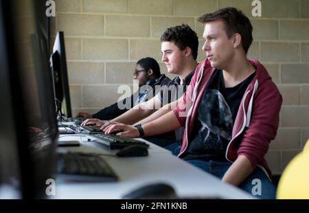 Sesta forma di studenti, giovani in istruzione, due adolescenti che collaborano agli schermi, 3 giovani maschi in sesta forma che lavorano insieme Foto Stock