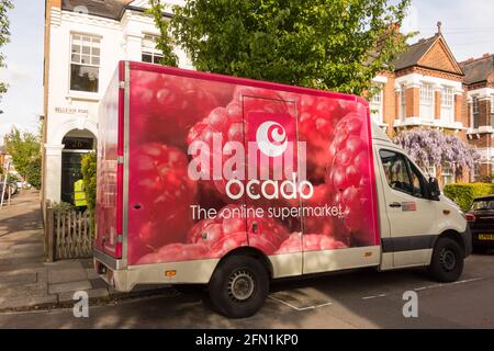 Primo piano vista laterale dei lamponi su un pulmino di consegna Ocado e autista su una strada suburbana a Londra, Inghilterra, Regno Unito Foto Stock