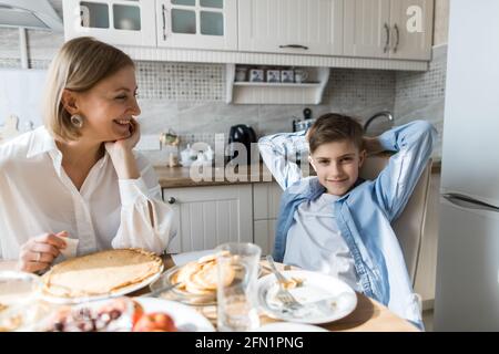 Una donna adulta in cucina sembra che un bambino mangia. Foto Stock