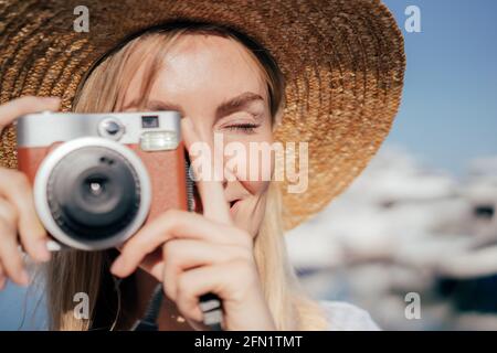 Primo piano di una donna che scatta una foto con una fotocamera in una giornata estiva soleggiata. Foto Stock