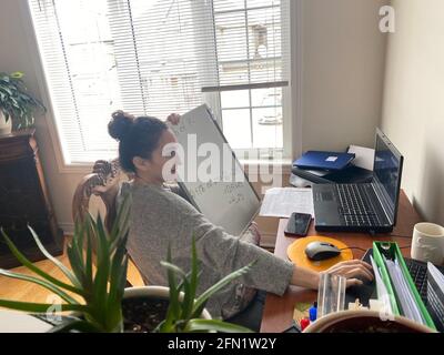INSEGNANTE LAVORA ONLINE CON LA SUA CLASSE DURANTE LA PANDEMIA COVID-19. Foto Stock