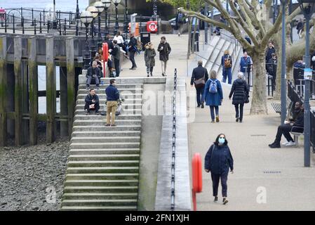 Londra, Inghilterra, Regno Unito. Persone che camminano lungo la South Bank e si siedono sulle scale fino al Tamigi Foto Stock
