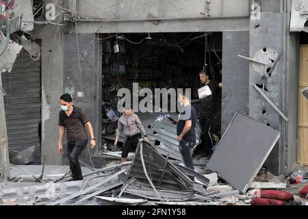 (210513) -- CITTÀ DI GAZA, 13 maggio 2021 (Xinhua) -- i palestinesi si trovano fuori da un negozio danneggiato a seguito di attacchi aerei israeliani a Gaza, 13 maggio 2021. La tensione tra Israele e i gruppi militanti nella striscia di Gaza è proseguita giovedì, mentre i funzionari del ministero della sanità gestito da Hamas hanno affermato che il numero delle vittime nell'enclave costiera assediata è salito a 83. Il ministero della salute a Gaza ha detto in un breve messaggio di testo inviato ai giornalisti che dall'inizio della tensione di lunedì, 83 palestinesi sono stati uccisi, tra cui 17 bambini e sette donne, aggiungendo che 487 sono stati feriti. (Foto di Rizek Abdeljawad/Xinh Foto Stock